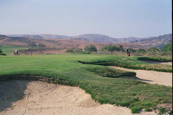 The golfer looks straight down the 40 yard long rectangular 10th green by staying close to these bunkers. 