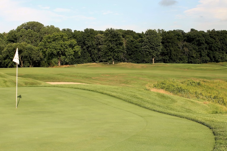 Some might wonder how nine holes that measure 3,230 yards can challenge good players. The depth of the hazards and the green contours are two immediate answers. Additionally, several tee balls like the one here hit into upslopes and kill much roll. Also, given that the best angle into the 4th green and most level stances are afforded from the outside of the dogleg, the hole plays longer than its 370 yards. 
