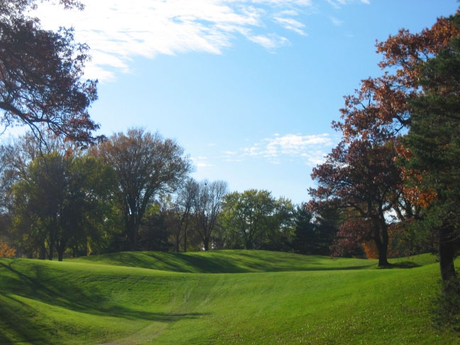 Tee shot on the thirteenth. The shaded area to the left is fairway making it larger than it appears in this picture. The crest of the hill is about 200 yards from the tee. A flat spot 80 yards from the green can be reached by any shot that clears that crest within the confines of the fairway. Alternately, a good tee shot can carry the trees on the right.
