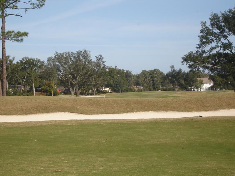 Third green as seen from the tee shot landing area, just the top of the flag visible.