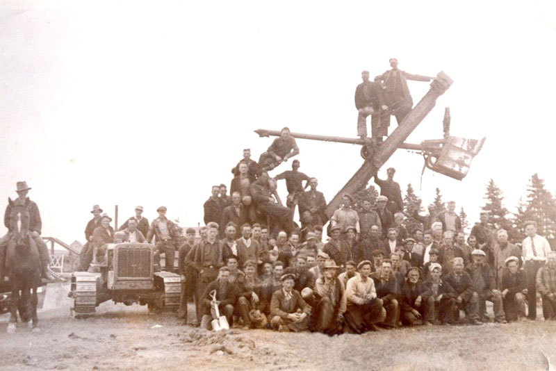 The construction crew and equipment, with a young Geoff Cornish in a shirt and tie on the far right supervising.