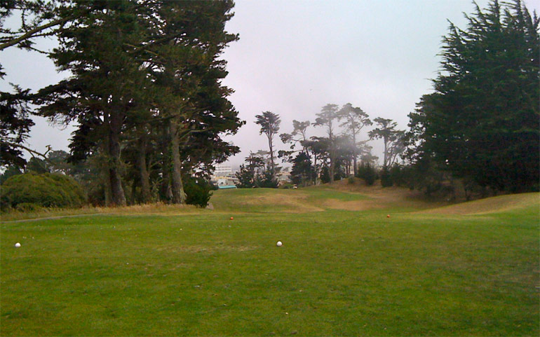 The 11th hole from the tee. The green is just to the left of the green roof in the distance.