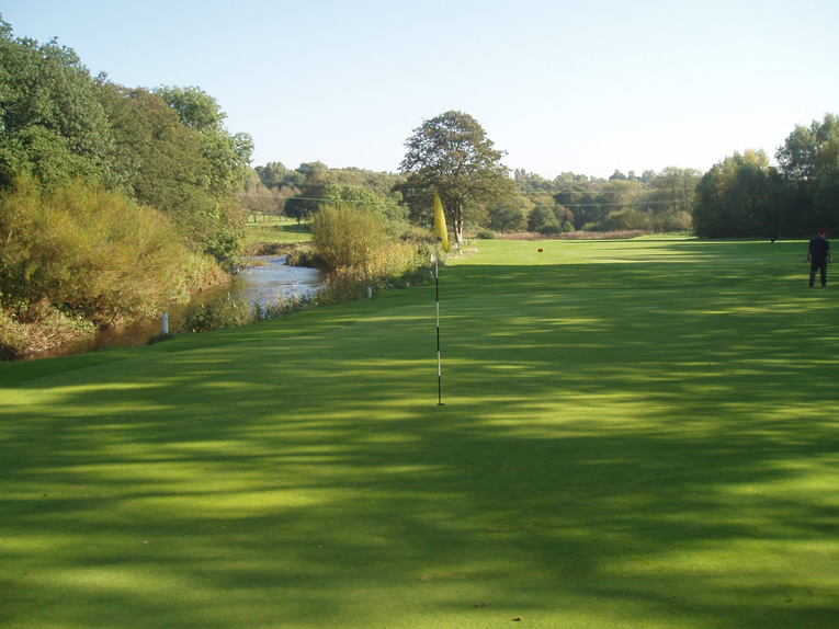 This view from behind the green highlights the river's close proximity to the edge of the green. The author disagrees with the club policy of treating the water hazard as out of bounds.