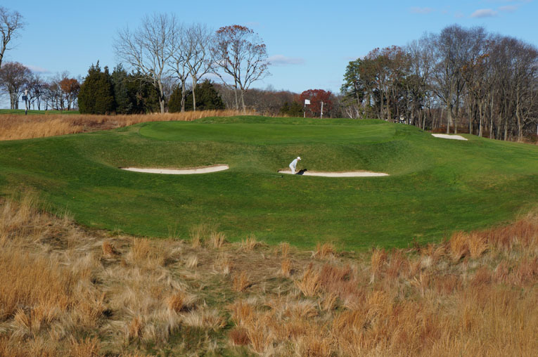 The golfer provides a sense of scale to the nasty pits that front the seventeenth green. One also gains a sense of the wicked nine yard long false front. If the golfer in the bunker doesn't carry his recovery shot at least twenty yards, he will likely get another chance.